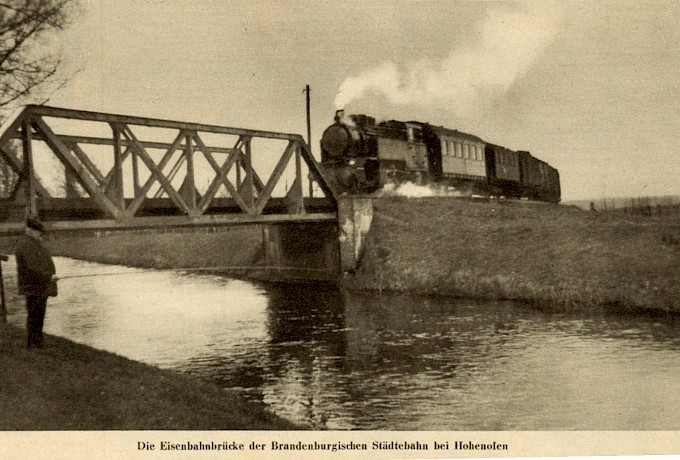 Hohenofen – 1925 – Ein Zug der Brandenburgischen Städtebahn überquert um 1925 die Dossebrücke neben der Papierfabrik Hohenofen Richtung Sieversdorf.